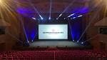 Escenario del auditorio preparado para un evento con iluminación y pantalla central