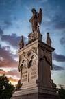 Monumento funerario con escultura de ángel bajo un cielo crepuscular