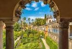 Vista panorámica de los jardines del Alcázar enmarcada por un arco de piedra