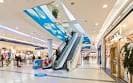 Interior del centro comercial con escaleras mecánicas y tiendas