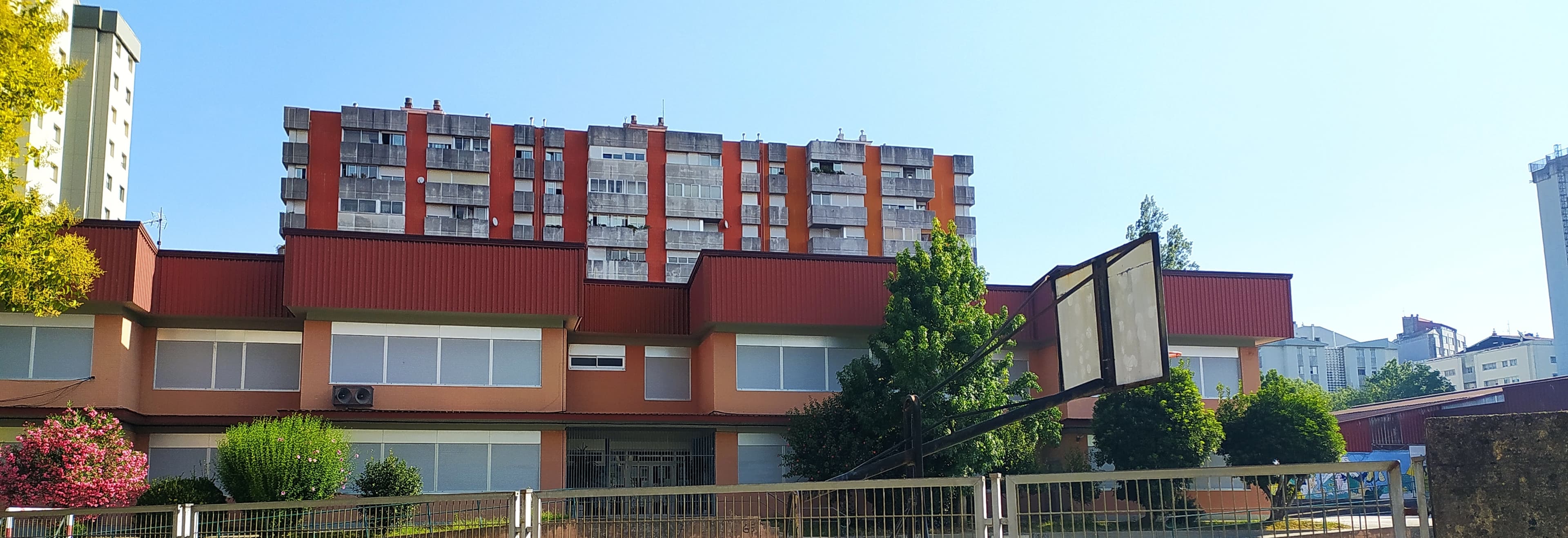 Vista exterior del edificio principal del CEIP Campolongo bajo un cielo azul