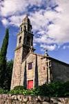 Vista de la fachada principal de la Iglesia de Santa María de Xeve con su torre campanario y cielo azul