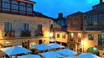 Plaza con terrazas y edificios históricos iluminados al anochecer en Pontevedra