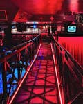 Interior del club con pasarela elevada y luces rojas