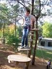 Joven en una plataforma de árbol preparándose para un circuito de aventura