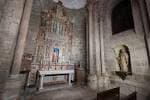 Interior de una capilla de la Catedral de Santiago con retablo y paredes de piedra
