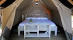 Interior de una tienda de glamping con cama y mobiliario en Isla de Ons
