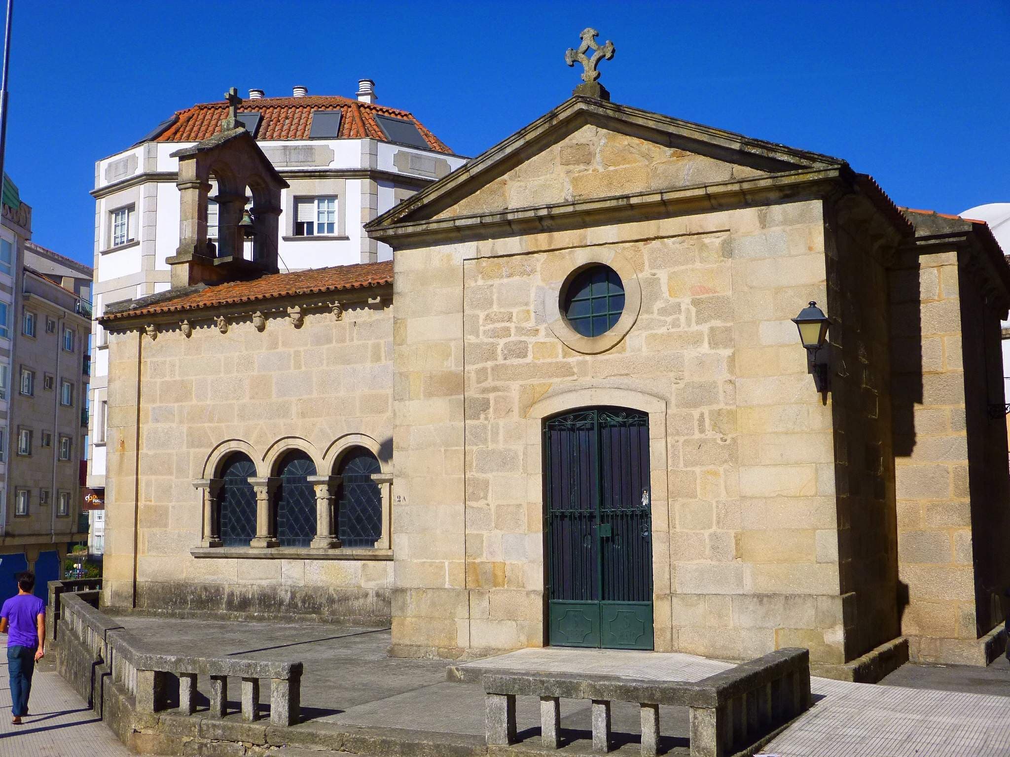 Vista frontal de la Capilla de San Roque bajo un cielo azul.