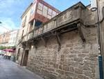 Fachada de piedra del Pazo de los Condes de San Román con balcón de madera