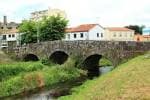 Antiguo puente de piedra sobre el río Sar con casas tradicionales al fondo