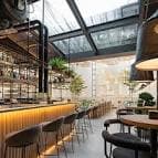 Zona de barra y mesas bajo un techo acristalado