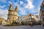 Vista panorámica de la Plaza de la Peregrina con la iglesia y edificios circundantes bajo un cielo azul