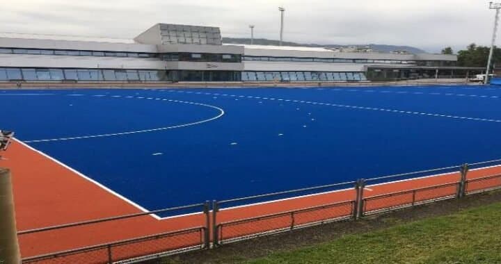 Campo de hockey de hierba azul con edificio al fondo