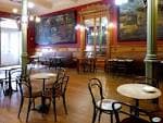 Interior del Café Moderno con mesas y sillas vacías, destacando la decoración clásica.