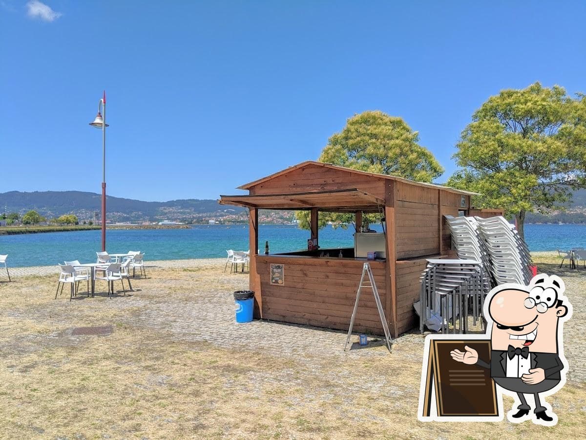Vista exterior del chiringuito junto al mar con mesas al aire libre
