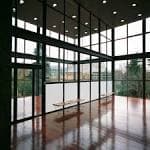 Interior diáfano y luminoso con grandes ventanales y suelo reflectante, ideal para eventos