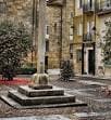 Crucero de piedra en la Praza de San Martiño con edificios históricos al fondo