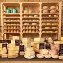 Exposición de quesos variados en estanterías de madera y mostrador