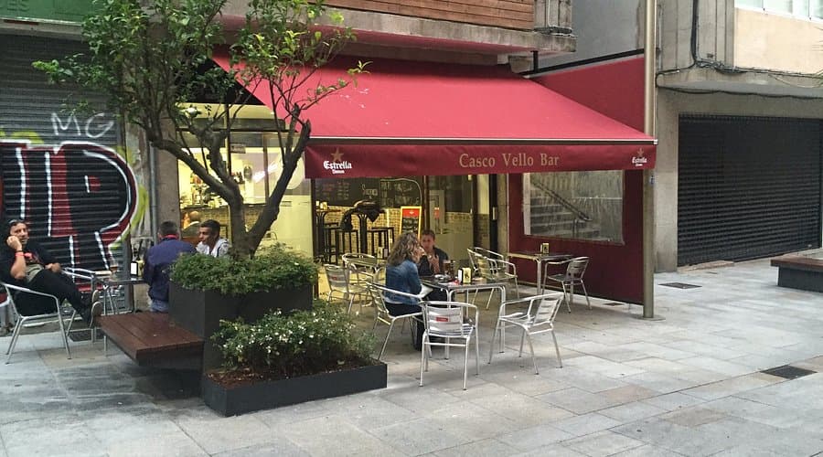 Exterior de un bar con toldo rojo y terraza en Vigo