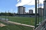 Perspectiva del campo de fútbol con gradas y edificios residenciales al fondo