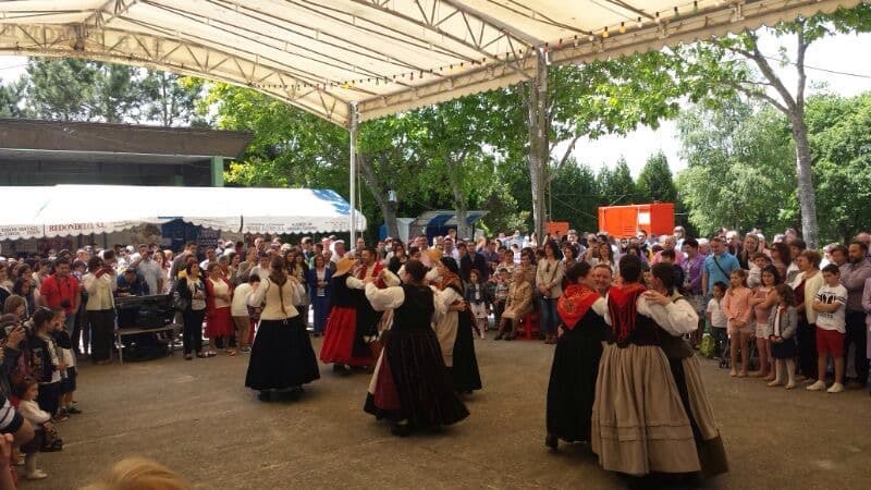Actuación de danza tradicional gallega bajo una carpa en un campo de fiesta