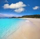 Extensa playa de arena blanca y mar turquesa bajo un cielo azul