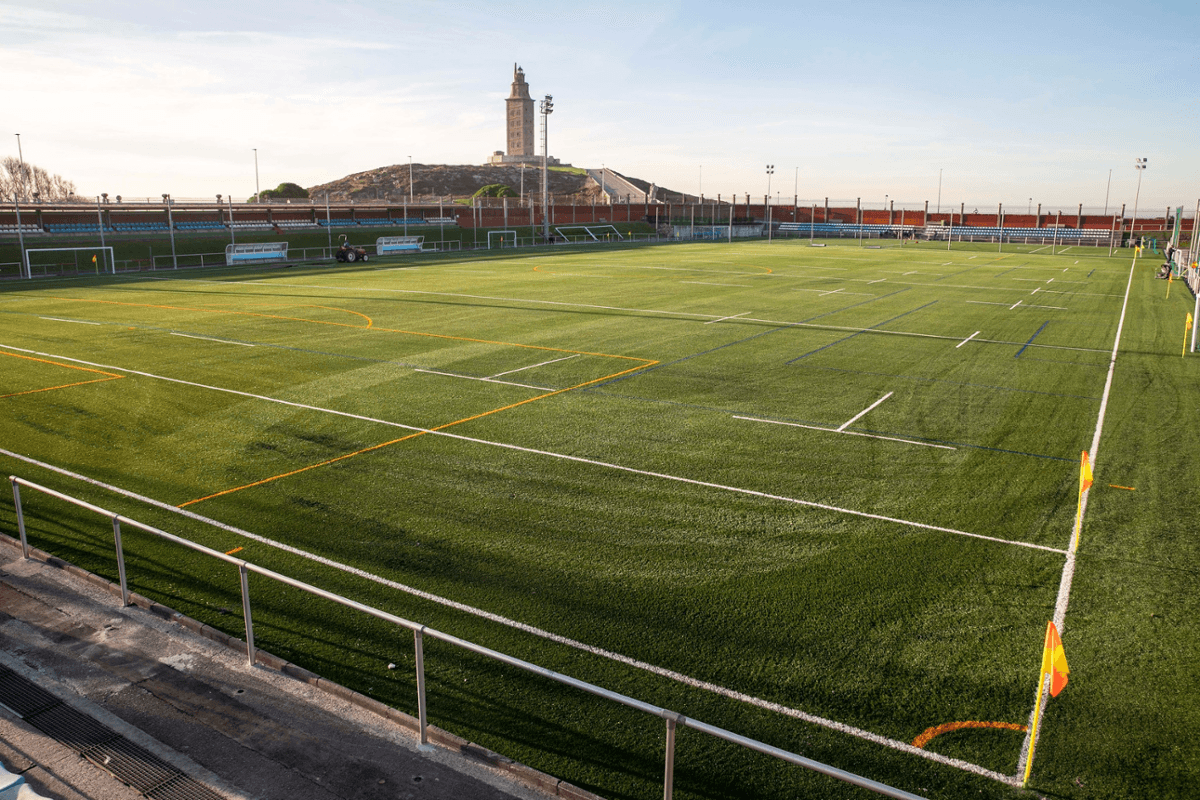 Campo de fútbol principal de la Ciudad Deportiva de la Torre con la Torre de Hércules al fondo