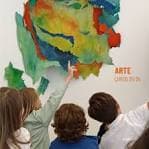 Niños participando en un taller de arte con un mural colorido