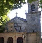 Primer plano de la fachada y campanario de la Iglesia de Santa Cristina de Lavadores entre la vegetación
