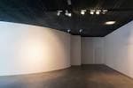 Galería interior vacía con paredes blancas curvas y sistema de iluminación