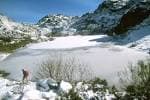 Lago helado rodeado de montañas nevadas en Pena Trevinca