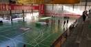 Interior del pabellón con cancha deportiva verde y personas