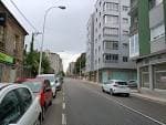 Calle Rosalía de Castro con edificios modernos y coches aparcados