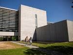 Edificio moderno del Campus Auga con fachada de piedra y ventanales, con estudiantes