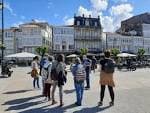 Grupo de personas en una plaza de Betanzos con edificios históricos al fondo