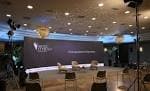 Escenario de evento con gran pantalla LED y asientos para ponentes