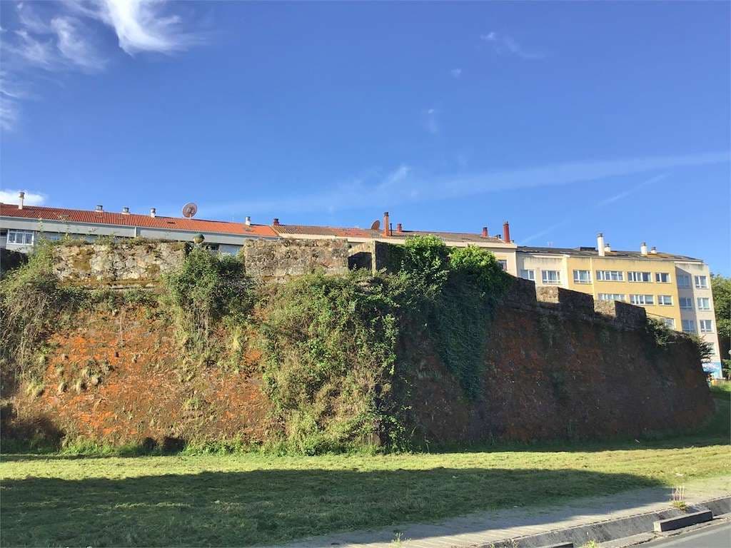 Vista exterior del Baluarte de Canido con vegetación y edificios al fondo