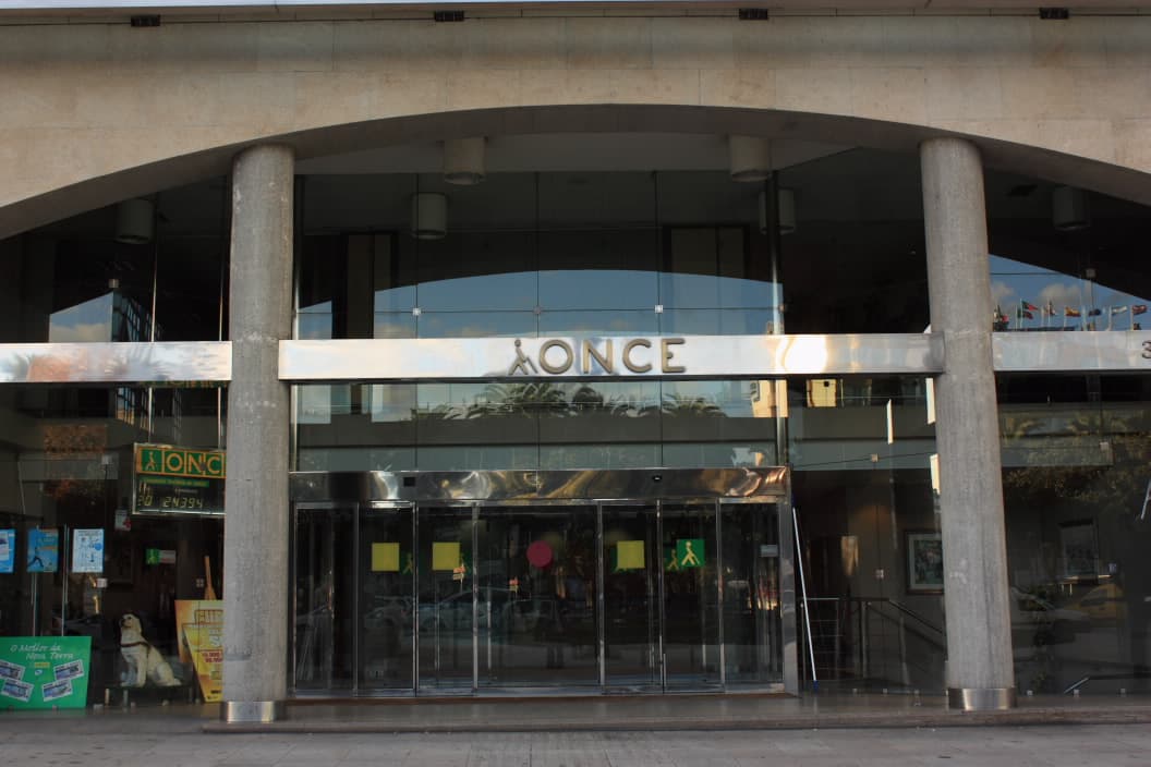 Entrada principal del edificio de la ONCE con puertas de cristal y columnas