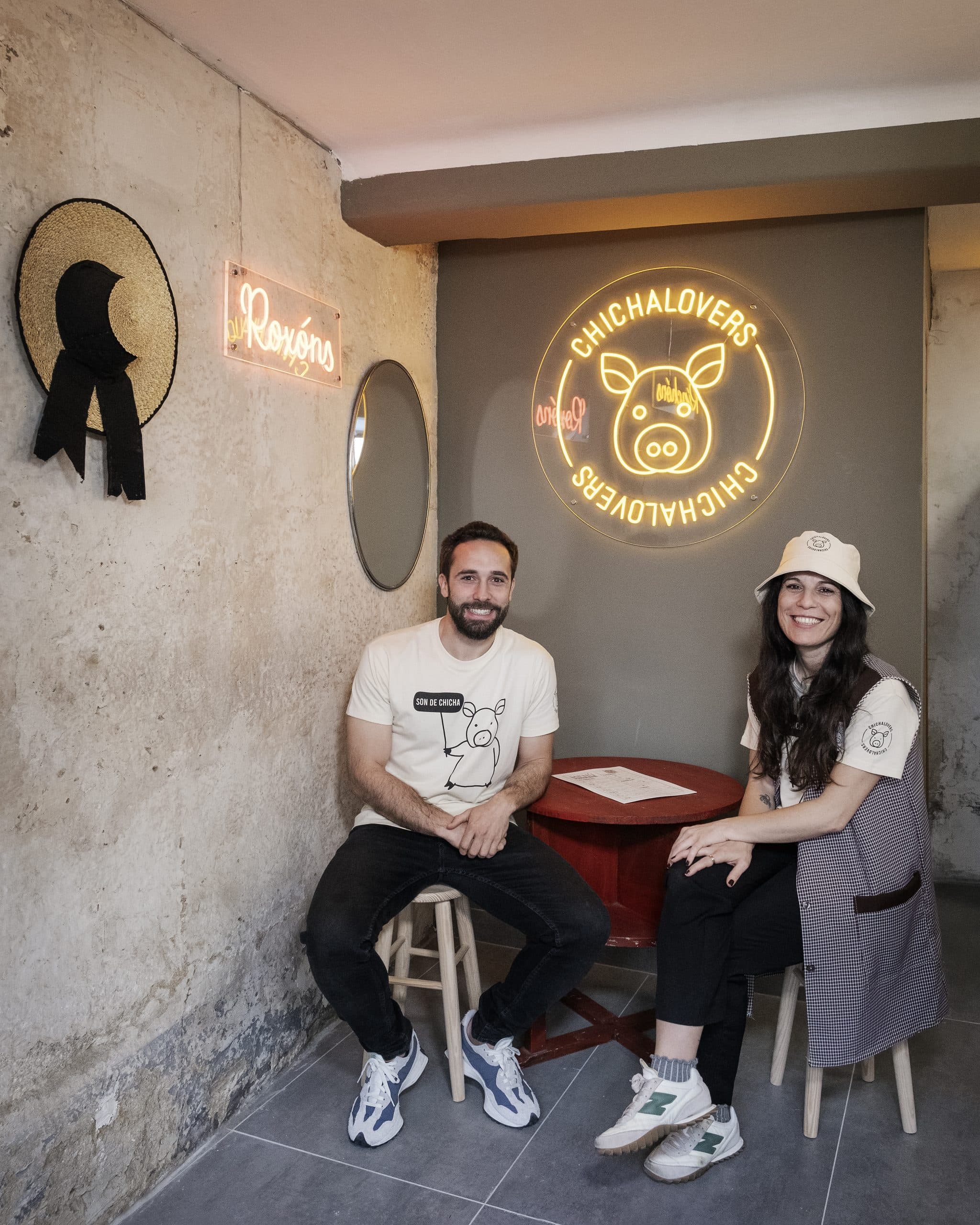 Interior del local Chichalovers con dos personas y el letrero de neón del logo del cerdo