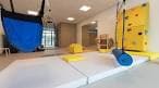 Sala de terapia ocupacional con colchonetas y pared de escalada