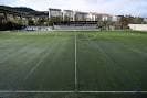 Campo de fútbol de Os Carrís desde el césped, mostrando las gradas y edificios circundantes.