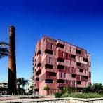 Vista exterior de edificio moderno con fachada de ladrillo y chimenea industrial