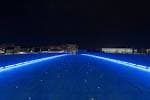 Reflejos de luces azules en el agua cerca del Puente del Burgo por la noche