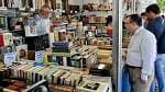 Puesto de libros con personas explorando la selección en la Feria del Libro