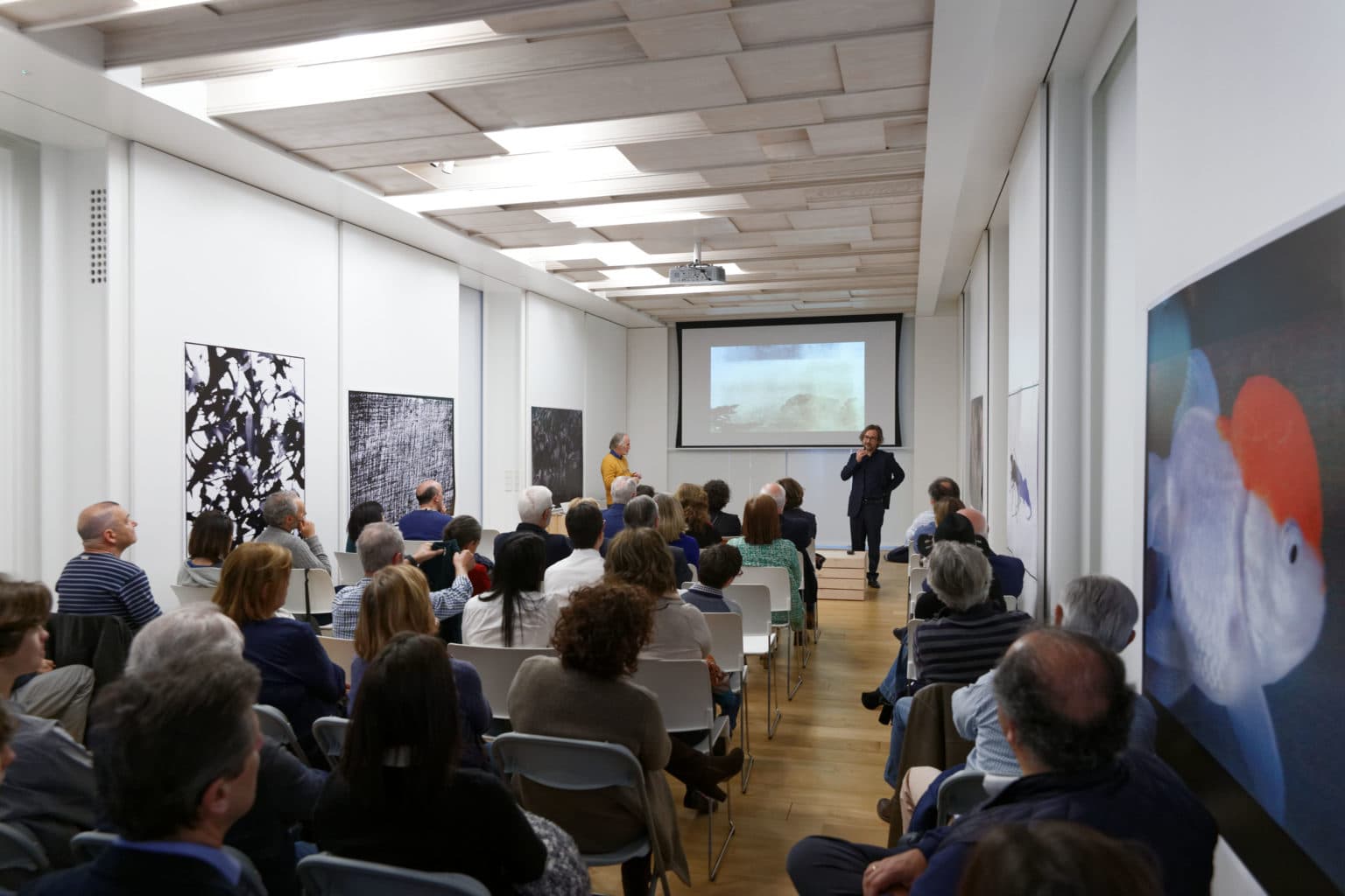 Sala de conferencias con público y pantalla de proyección en Espacio Nemonon
