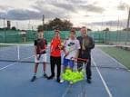 Jugadores y entrenador en una cancha de tenis del club