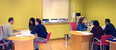 Sala de reuniones con personas en mesas redondas y paredes amarillas