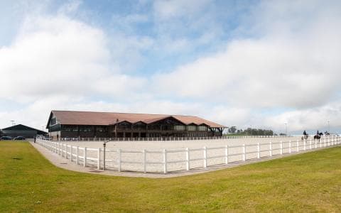 Vista exterior del Centro Hípico Casas Novas con pista de arena y edificio principal
