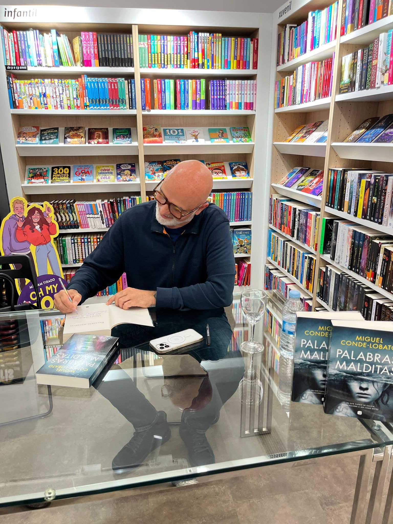 Autor firmando libros en el mostrador de una librería
