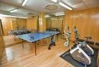 Sala de ocio y gimnasio con mesa de ping-pong y bicicletas estáticas
